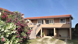 Ein zweigeschossiges Haus mit rotem Ziegeldach, einem Balkon und einer Garage.