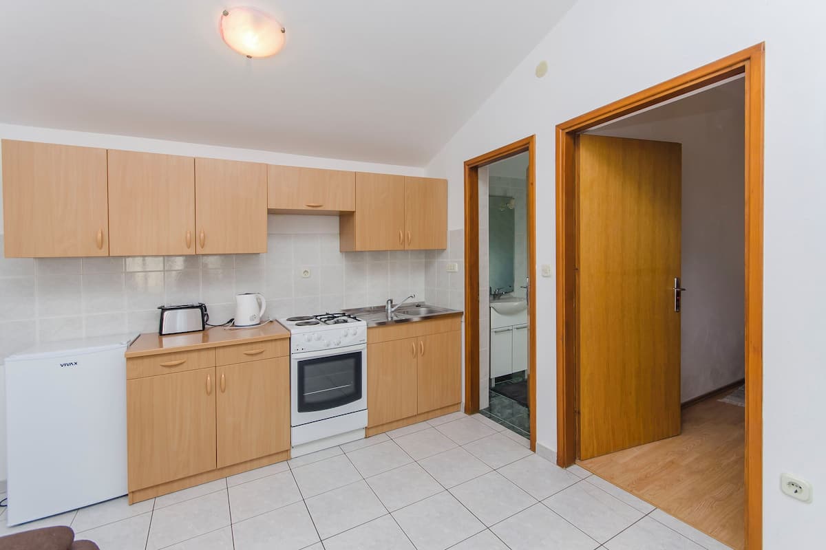 A compact kitchen with wooden cabinets, a gas stove, a sink, and a refrigerator.