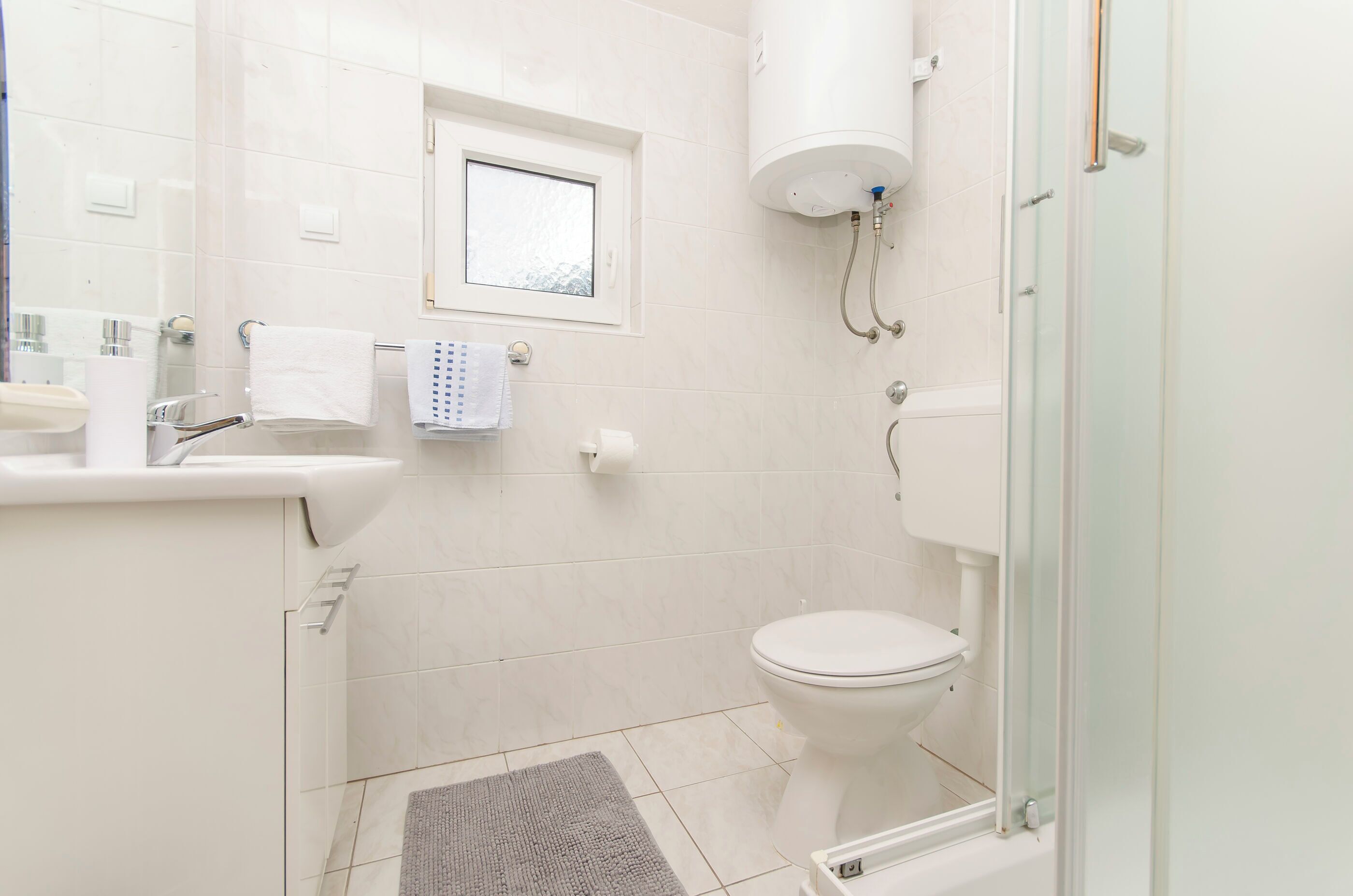 Een moderne badkamer met toilet, wastafel en douche.