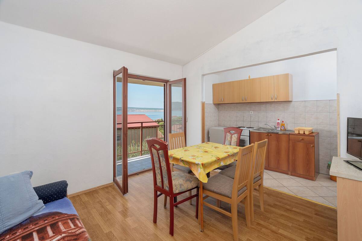 A compact living space with a balcony, a dining area, and a kitchenette.