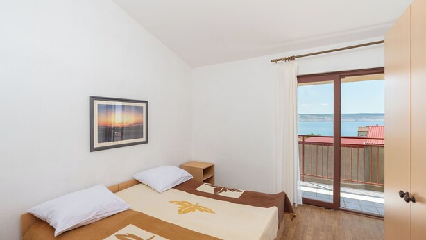 Un dormitorio con cama, mesita de noche, un cuadro enmarcado en la pared y un balcón con vistas.