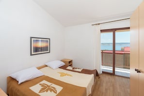 A bedroom with a bed, a nightstand, a framed picture on the wall, and a balcony with a view. - Apartment Sunny (Starigrad)