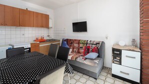 Una cocina compacta con armarios de madera, salpicadero de azulejos blancos, estufa y pileta.