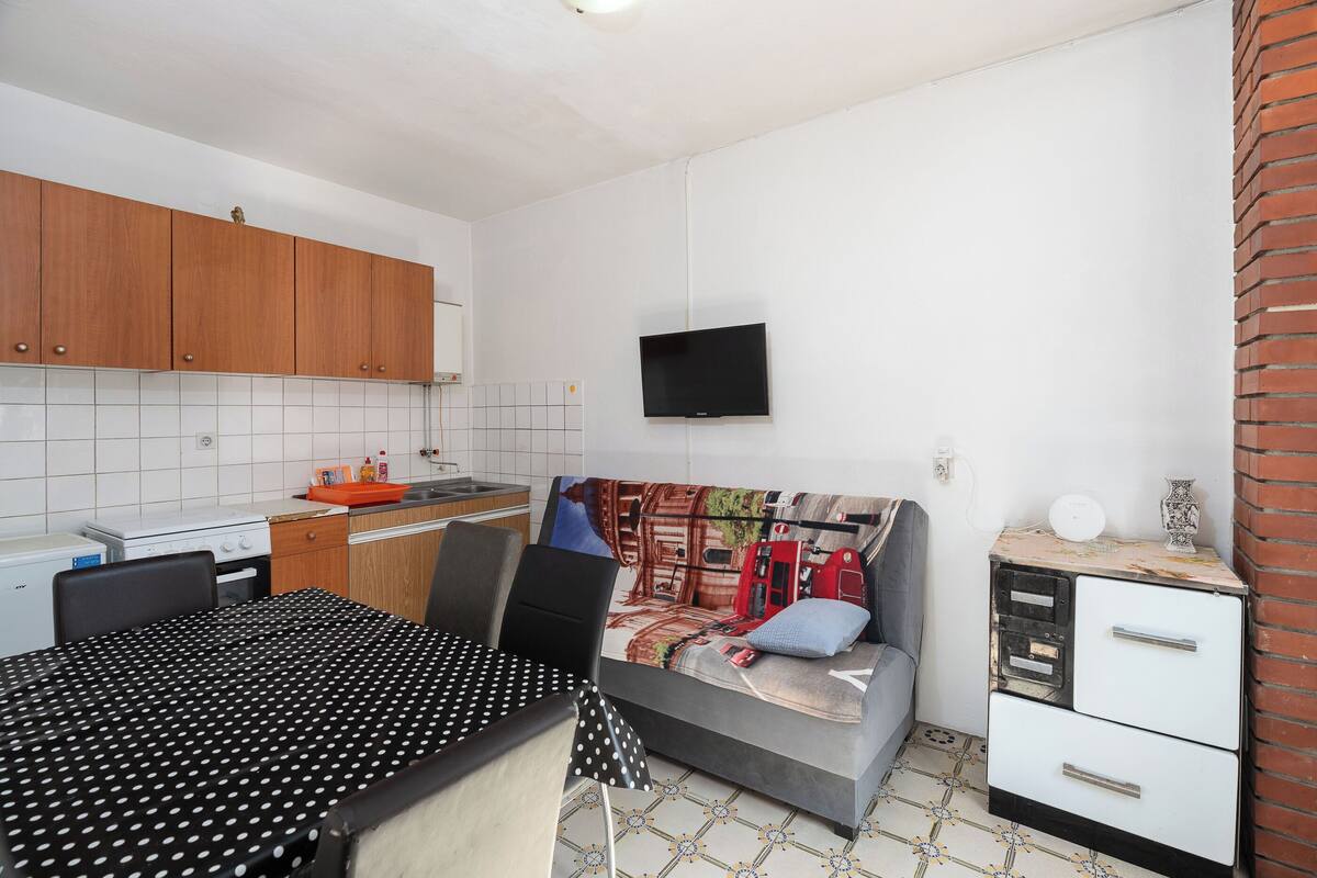 A compact kitchen with wooden cabinets, a white tiled backsplash, a stove, and a sink.