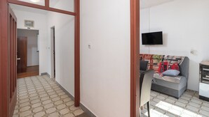 Una habitación con sofá, televisión en la pared y piso estampado.