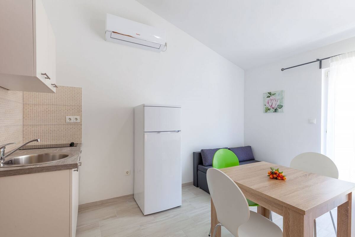 A modern kitchen with a built-in sink, a white refrigerator, and a dining area with a wooden table and chairs.