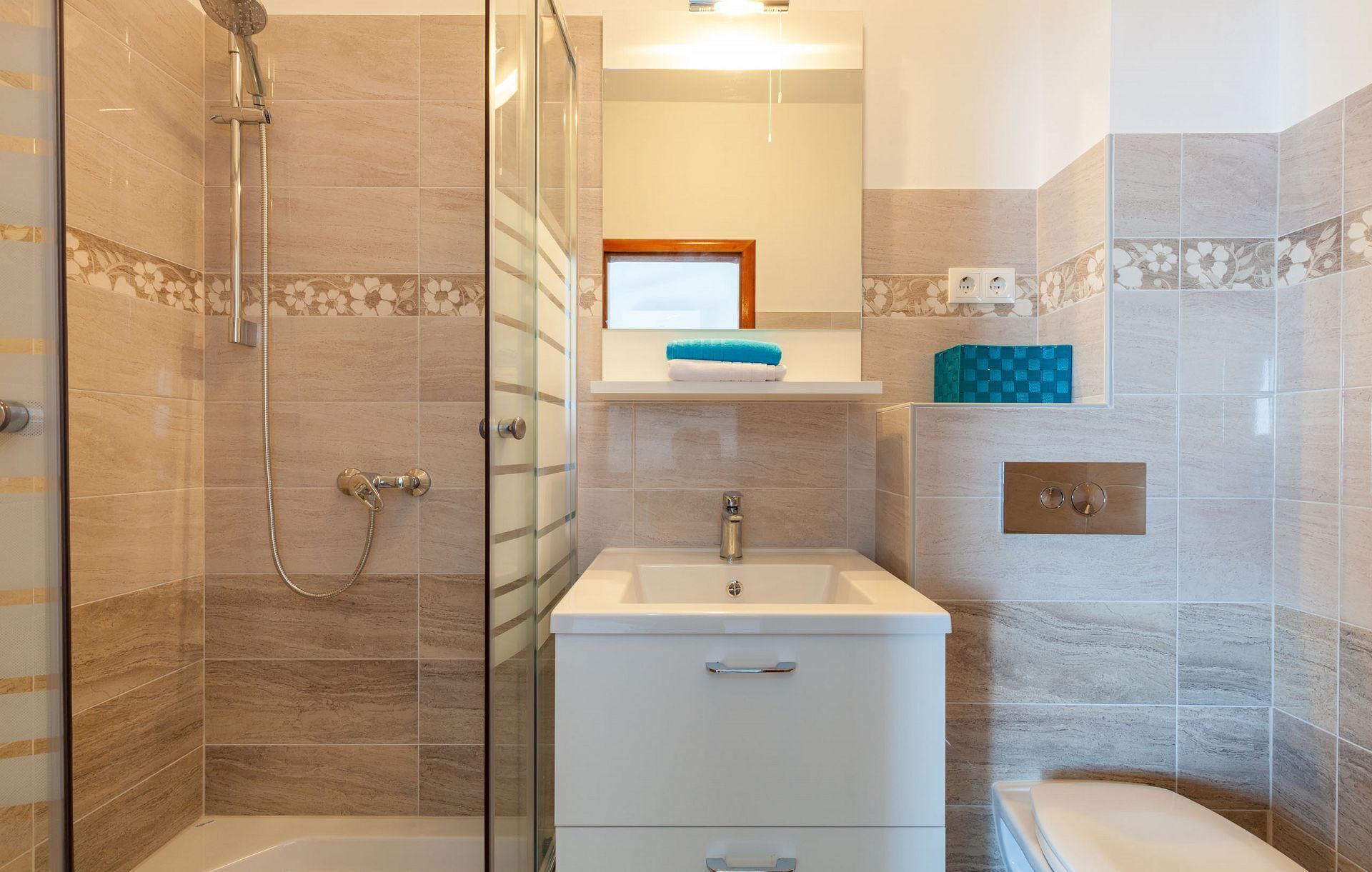 Une salle de bain avec une douche à parois de verre, un lavabo avec un miroir au-dessus et des toilettes.