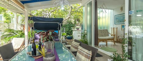 Un espace extérieur abrité, aménagé avec une table, des chaises et des plantes en pot.