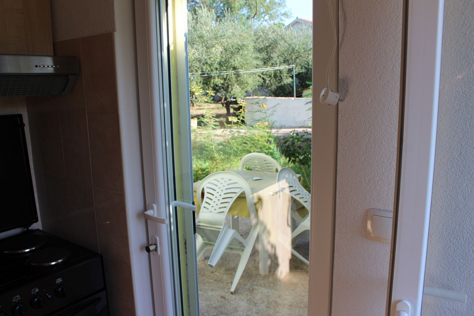 Une cuisine équipée d’une cuisinière et d’une fenêtre donnant sur un espace extérieur avec une table et des chaises.