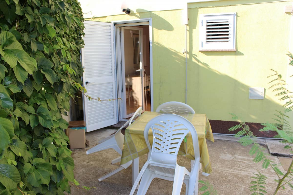 Une petite terrasse extérieure avec une table et des chaises, une porte et une fenêtre.