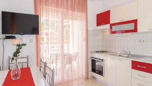 A modern kitchen with white and red cabinets, a built-in oven, and a sink. - Apartments Ljuba (Slivno)