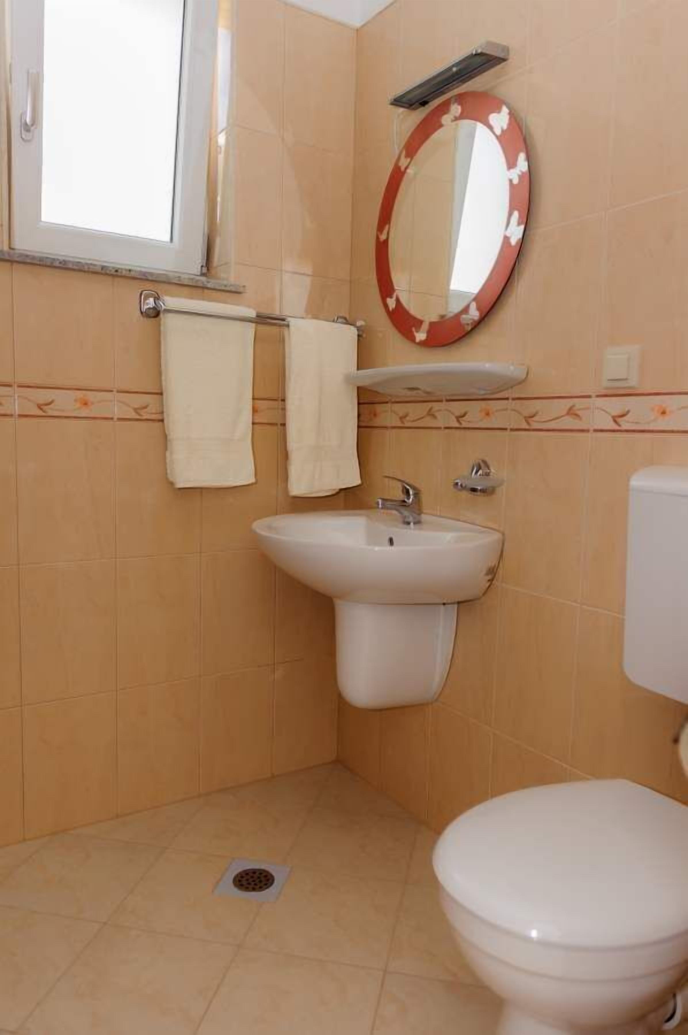 Un bagno con lavandino, WC e uno specchio con cornice decorativa.