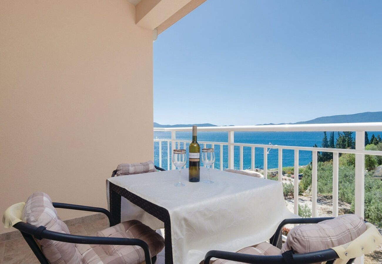 A balcony with a table and chairs, a bottle of wine, and a view of the sea and mountains.