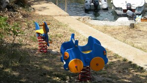 Een speeltuin met een treinrit in blauw en geel en een kleine blauwe schommel.