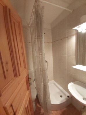 A bathroom with a wooden door, a shower with a lace curtain, a bathtub, and a sink. - Apartment Boto (Cres)