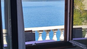Een kamer met uitzicht op een groot wateroppervlak en verafgelegen bergen.