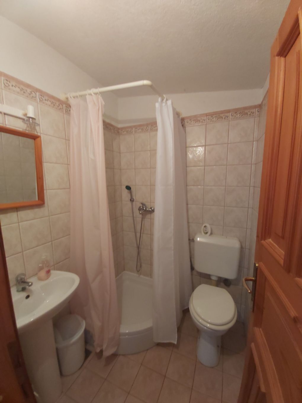 Ein Badezimmer mit Dusche, Toilette, Waschbecken und Spiegel.