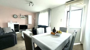 A modern living room with a dining table, chairs, a sofa, a TV, and a clock on the wall. - Apartment Anytime (Makarska)