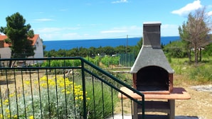 A stone outdoor oven with a view of the sea in the background. - Apartments Dia (Primosten)