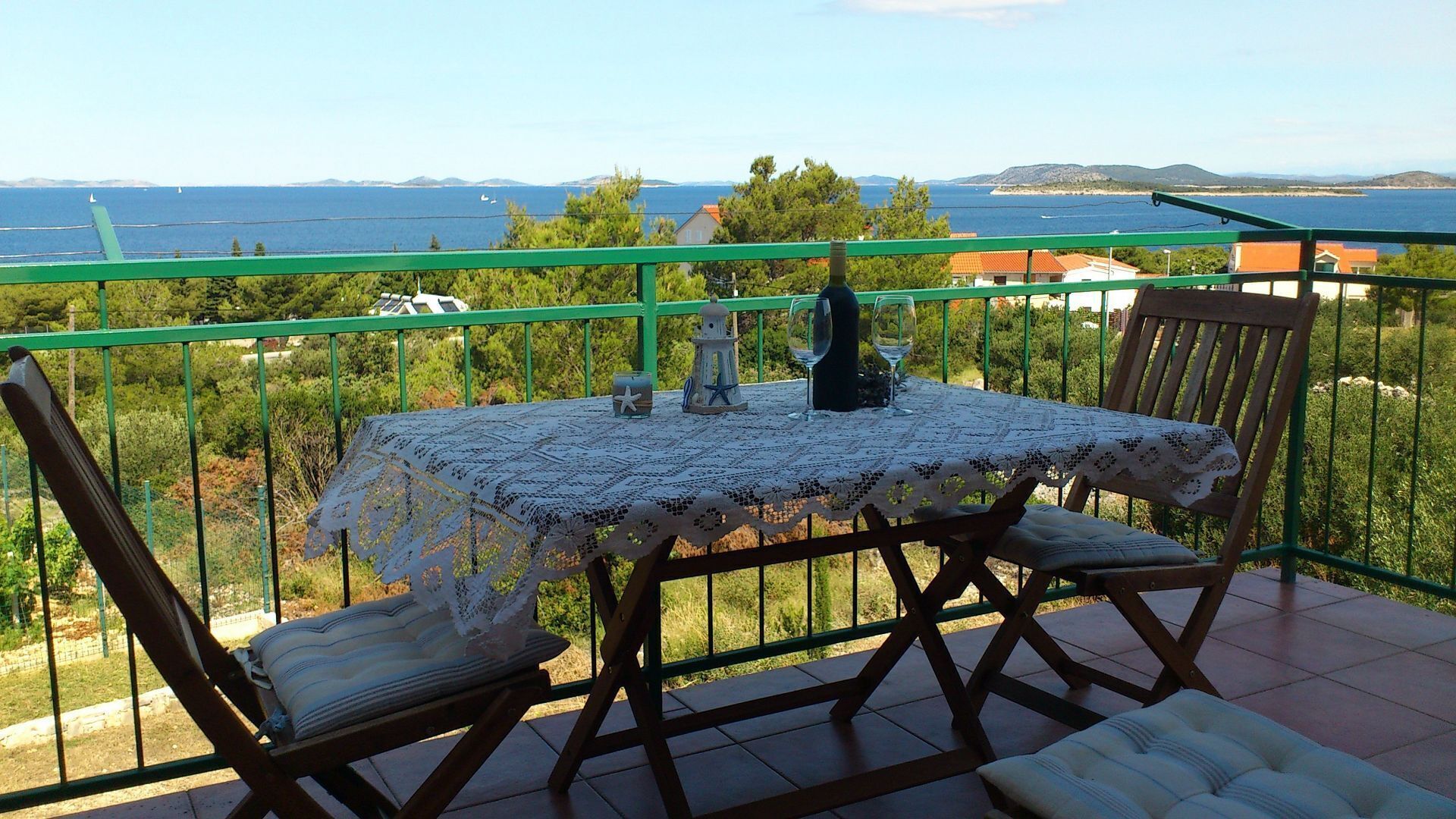 Ein Balkon mit Tisch und Stühlen, der auf eine Küstenlandschaft blickt.