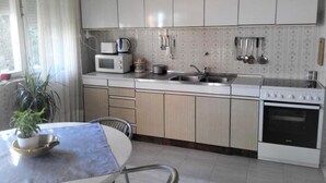 A compact kitchen with white cabinets, a microwave, a stove, and a sink. - Apartment Dane (Makarska)