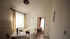 Ein Zimmer mit Esstisch, Stühlen, einer Couch und einem Bett.