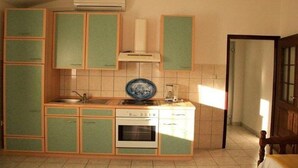 Eine Küche mit grünen Schränken, einem weißen Backofen und einem blauen Teller auf der Arbeitsfläche.