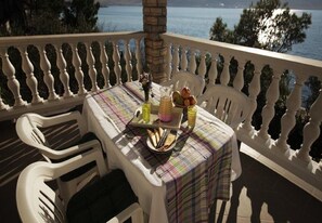 A table set on a balcony with a view of the sea, white chairs, and a tablecloth. - Apartments Ivan Z (Starigrad)