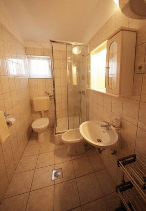 A compact bathroom with a toilet, a sink, and a shower enclosure. - Apartments Ivan Z (Starigrad)