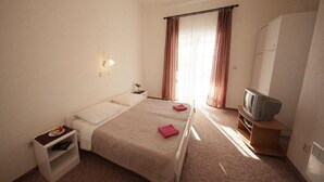 Ein Hotelzimmer mit Bett, Fernseher, Kleiderschrank und Nachttisch mit Lampe.