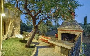 A stone patio with a brick oven, a hammock, and a bench. - House Niksi (Supetar)