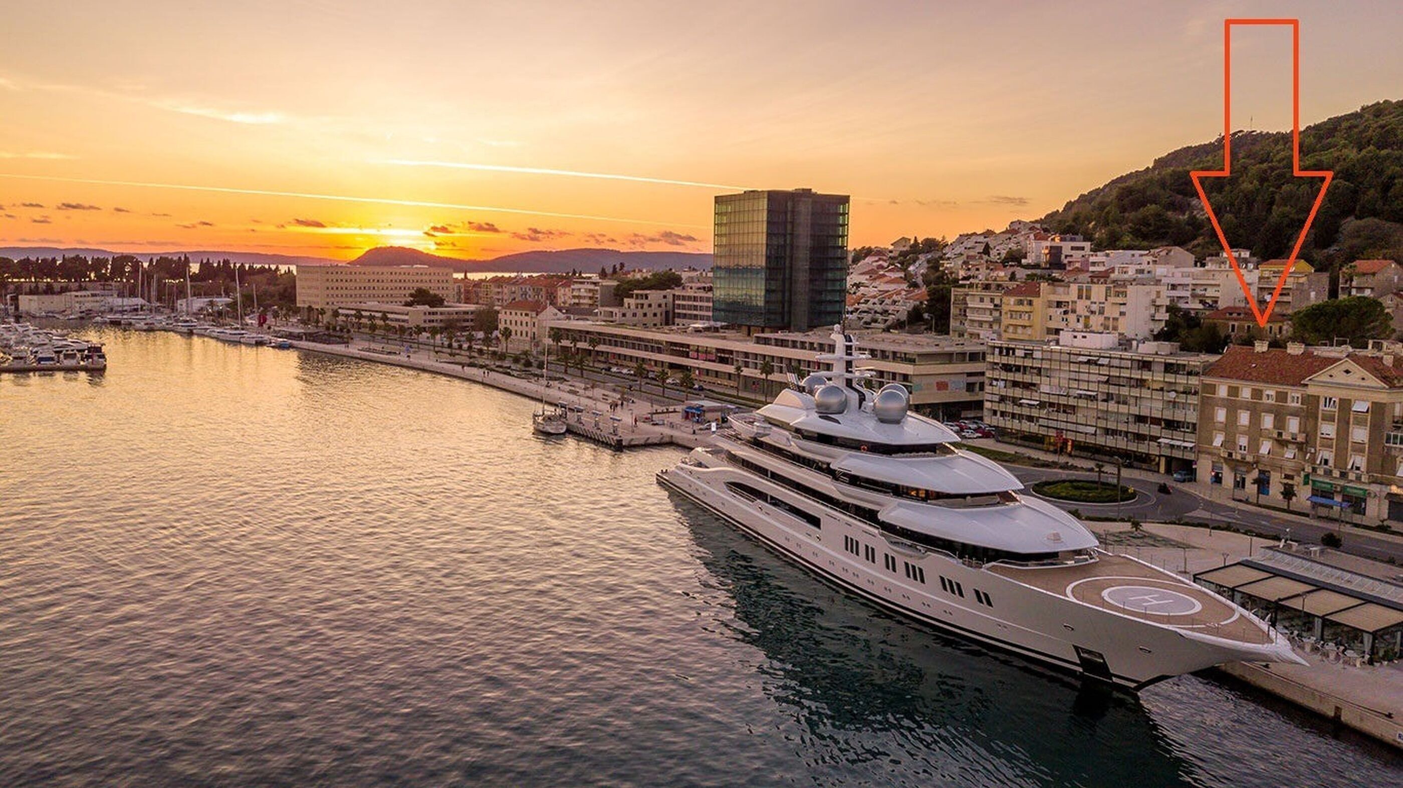 Marina à beira-mar com um iate grande atracado perto de um edifício moderno.