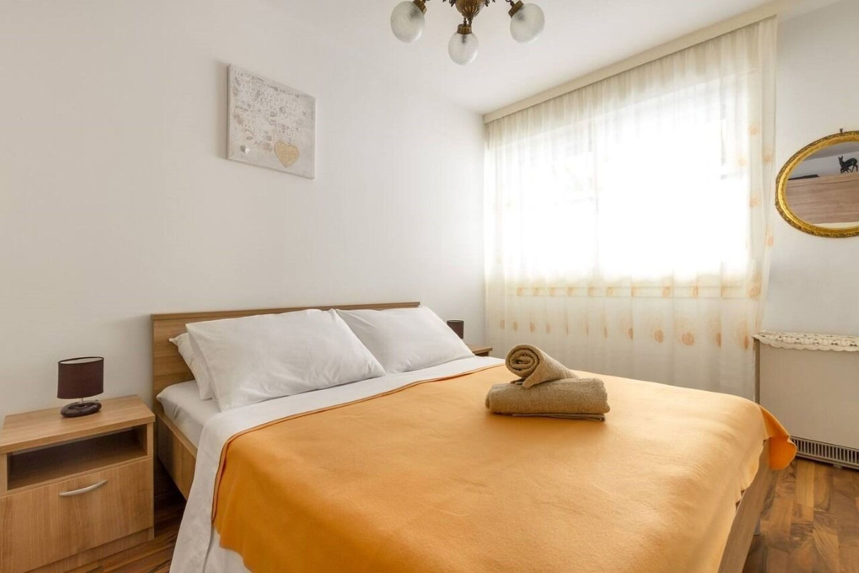A neatly made bed with a brown blanket, a bedside lamp, and a small table with a lamp.