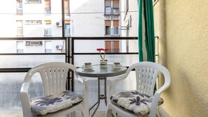 A balcony with two white plastic chairs and a small round table with three cups and a flower. - Apartment Deni (Split)