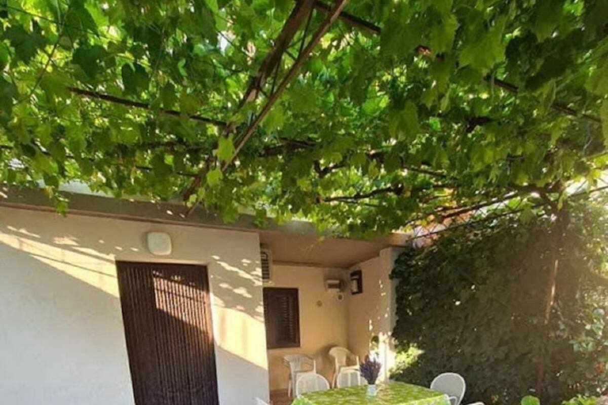 Une terrasse couverte avec une table et des chaises, entourée d’une végétation luxuriante et de fleurs d’hortensia.
