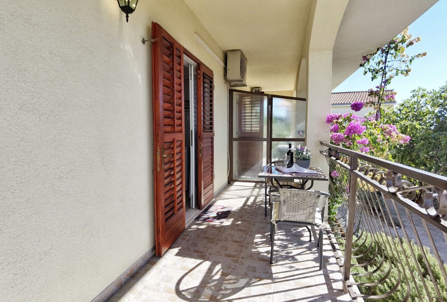 A balcony with a table and chairs, a potted plant, and a railing.
