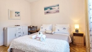 A neatly arranged bedroom with a bed, bedside tables, a dresser, and a painting on the wall. - Apartments Vinx (Rogoznica)