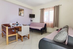 Ein Zimmer mit Esstisch, einer Couch, einem Bett, einem Fernseher und einem Bild an der Wand.