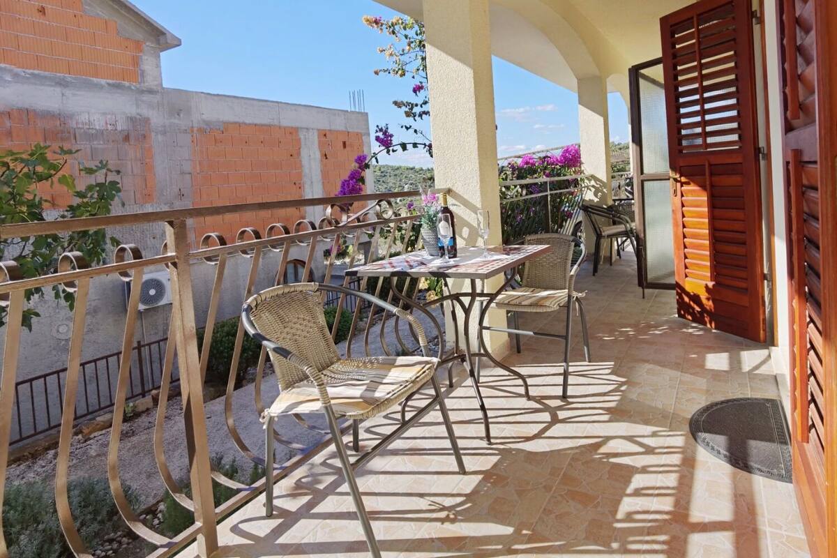 An outdoor patio with a table and chairs, a railing, and a view of the surrounding area.