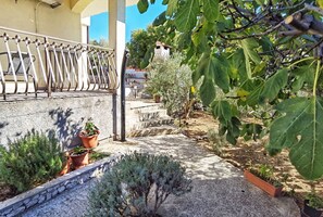 A garden with a stone pathway, potted plants, and a metal railing. - Apartments Vinx (Rogoznica)