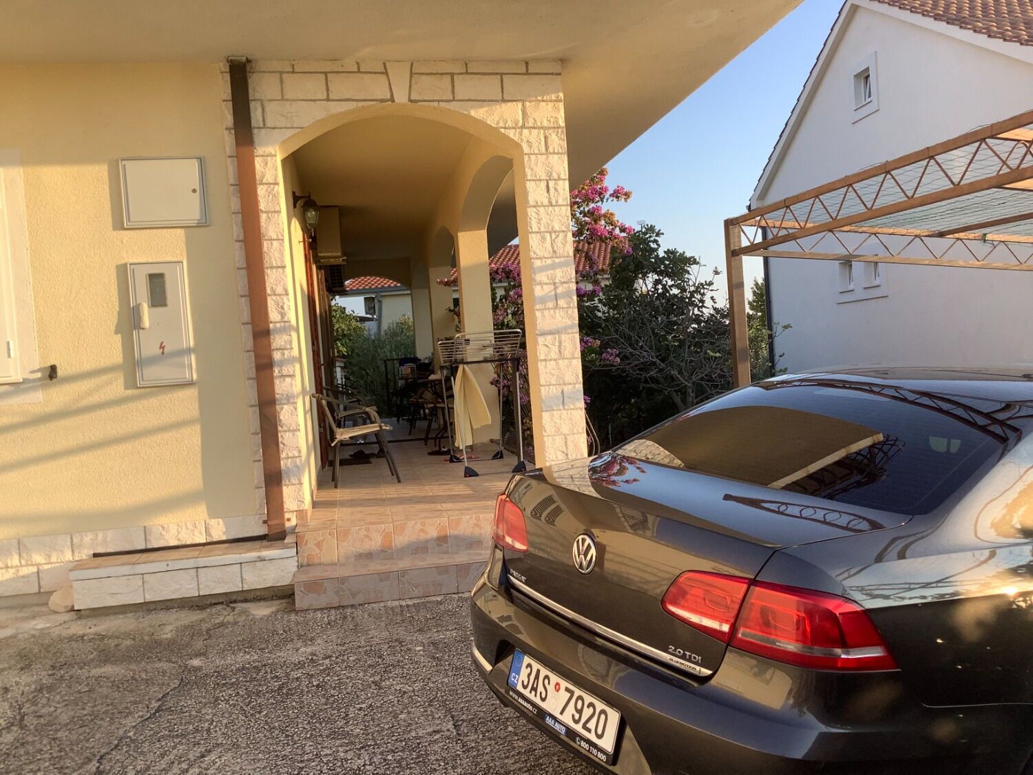 Ein schwarzer Volkswagen parkt auf einer Auffahrt mit einer Steinmauer und einem überdachten Patio.