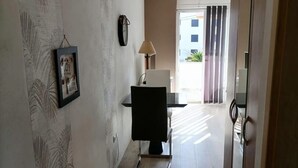 A hallway with a desk, chair, lamp, and a framed picture on the wall. - Apartments Dora 2 (Bibinje)