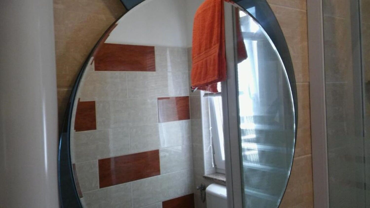 A bathroom with a tiled wall featuring a pattern of white and brown tiles.