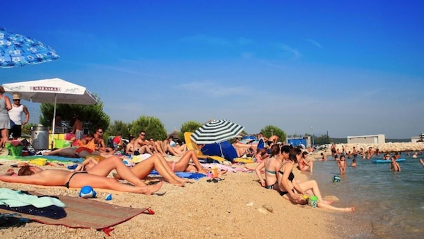 A crowded beach with people sunbathing and swimming. - Apartments Dora 2 (Bibinje)