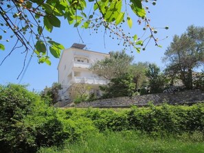 A two-story building with a stone wall and a balcony. - Apartments Josi (Rab)