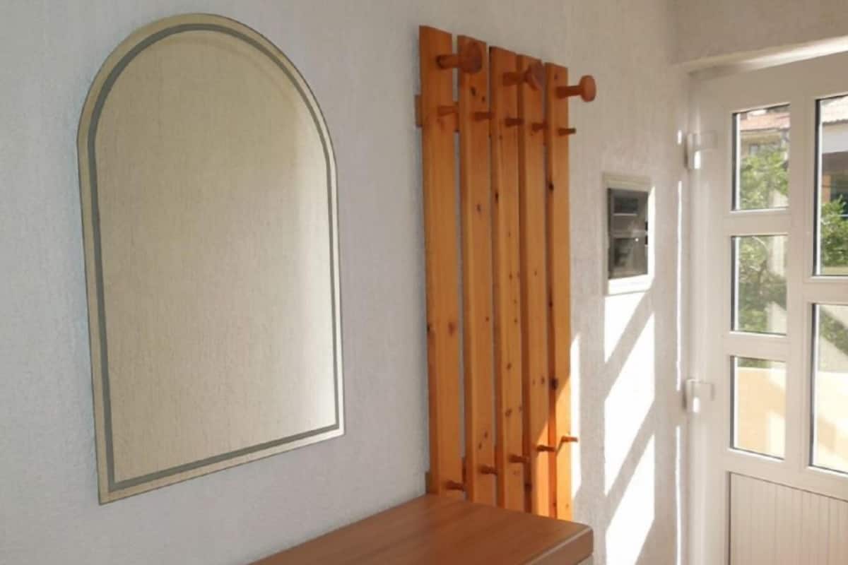 A room with a wooden cabinet, a mirror, and a window with a view of greenery.