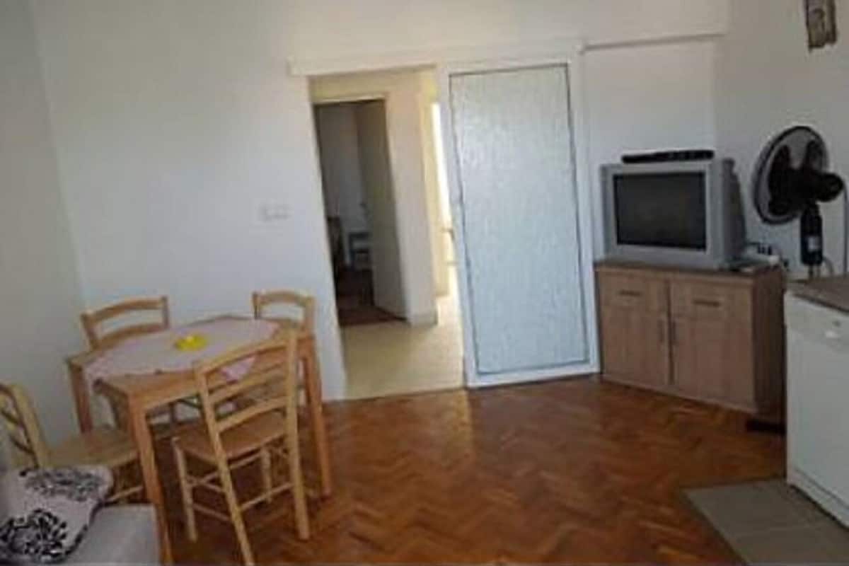 A small, compact living space with a dining area, a kitchenette, and a television.