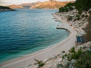 Una playa costera con una carretera curva y terreno rocoso.