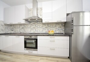 A modern kitchen with white cabinets, a stainless steel oven, and a refrigerator. - Apartment Sveto (Biograd na Moru)