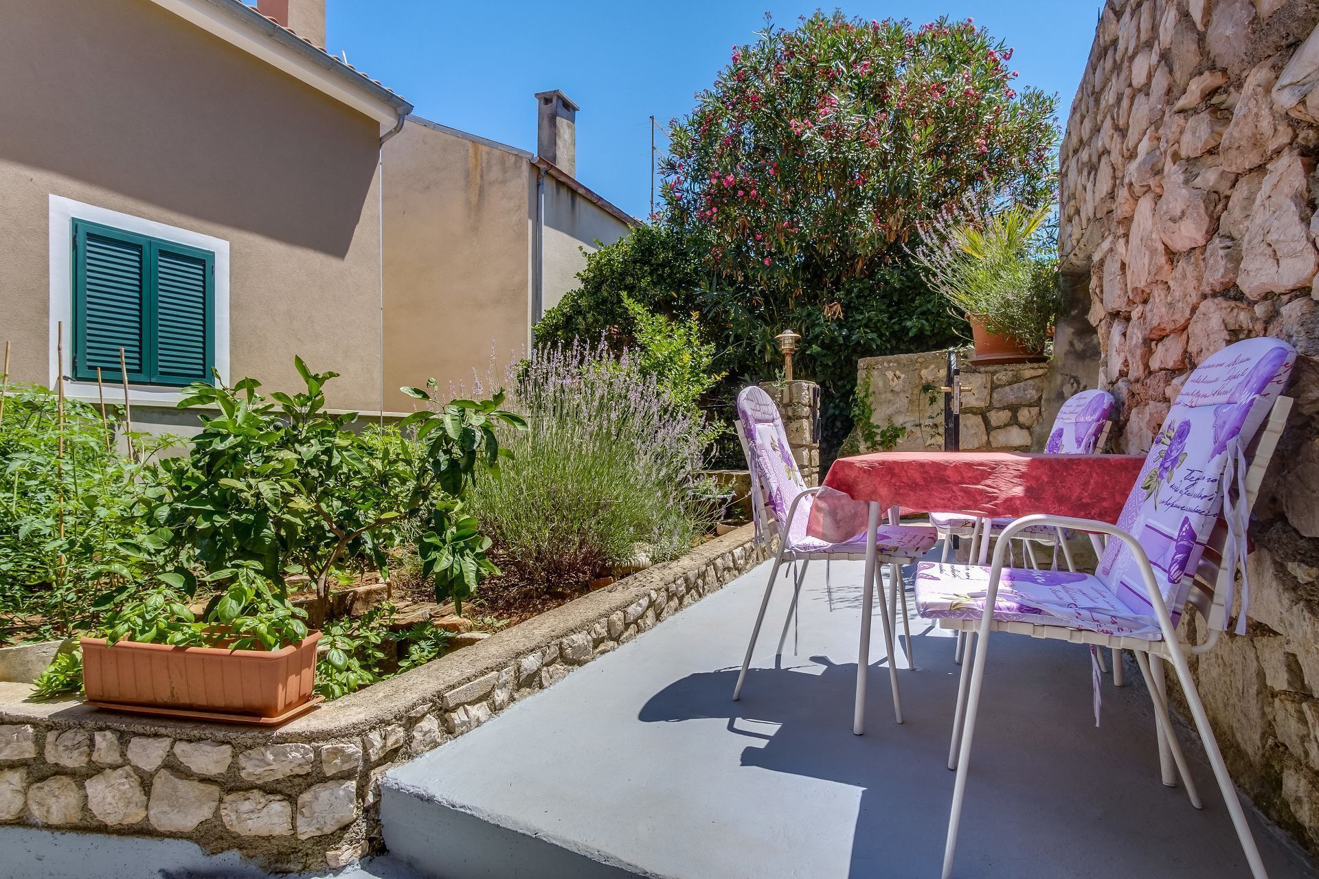 Eine Terrasse mit Gartenmöbeln, einer Steinmauer und verschiedenen Pflanzen.